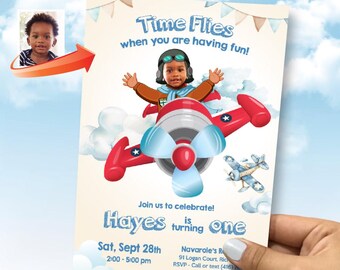 May include: A blue and white airplane birthday invitation with a cartoon pilot flying. The invitation says "Time Flies when you are having fun!" and "Join us to celebrate! Hayes is turning one". The date and time of the party are listed as "Sat, Sept 28th 2:00-5:00 pm".