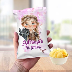 May include: A white chip bag featuring a watercolor illustration of a girl with a dragon, with the text "Adriana's 7th Birthday" in purple. A small bowl of potato chips sits next to the bag.