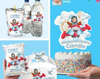 May include: A birthday party bundle with a blue and red aeroplane theme. The bundle includes a cake topper, water bottle labels, favour bags, and a favour box. The cake topper features a child in a pilot costume flying a red aeroplane. The favour bags and box feature the same aeroplane design with the child's name and age. The water bottle labels feature a smaller version of the aeroplane design.