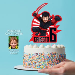 Puede incluir: Topper de pastel imprimible con un ninja de dibujos animados con un traje rojo y negro, sosteniendo una espada. El ninja tiene la cara de un niño superpuesta. El topper también incluye el nombre "Ernesto" y el número "6" en texto negro sobre un fondo rojo.