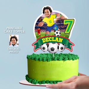 May include: A round cake topper featuring a football player illustration with the name DECLAN and the number 7. The design includes a football, a green banner, and a stadium background, displayed on a green frosted cake with grass-like texture.