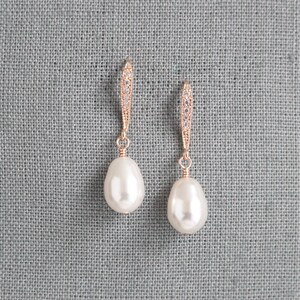 May include: A pair of rose gold earrings with a teardrop-shaped pearl and a crystal-encrusted dangle.