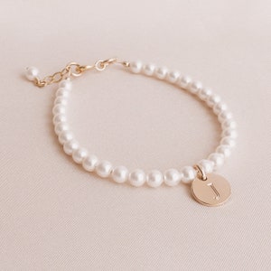 May include: A delicate pearl bracelet with a gold charm featuring the letter "J".