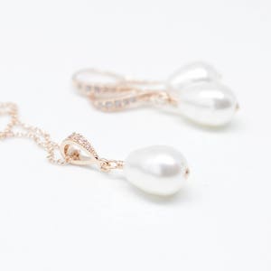 May include: A gold necklace with a pearl pendant and a pair of gold earrings with pearl drops. The necklace has a delicate chain and a small, sparkly pendant.