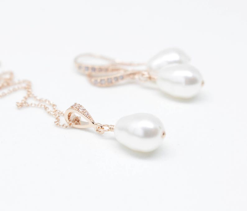 May include: A gold necklace with a pearl pendant and a pair of gold earrings with pearl drops. The necklace has a delicate chain and a small, sparkly pendant.