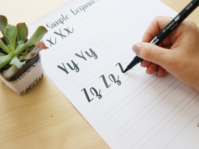 Pu&ograve; includere: Una mano che scrive le lettere "1212" su un foglio di carta rigato con un pennarello nero. La carta ha le parole "Simple beginner" e "Yy Yy" scritte su di essa.