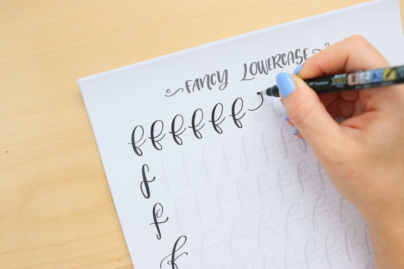 Puede incluir: Una persona practicando caligraf&iacute;a escribiendo la letra min&uacute;scula "f" repetidamente en una hoja de papel rayada. El texto "FANCY LOWERCASE" est&aacute; escrito en la parte superior de la p&aacute;gina.