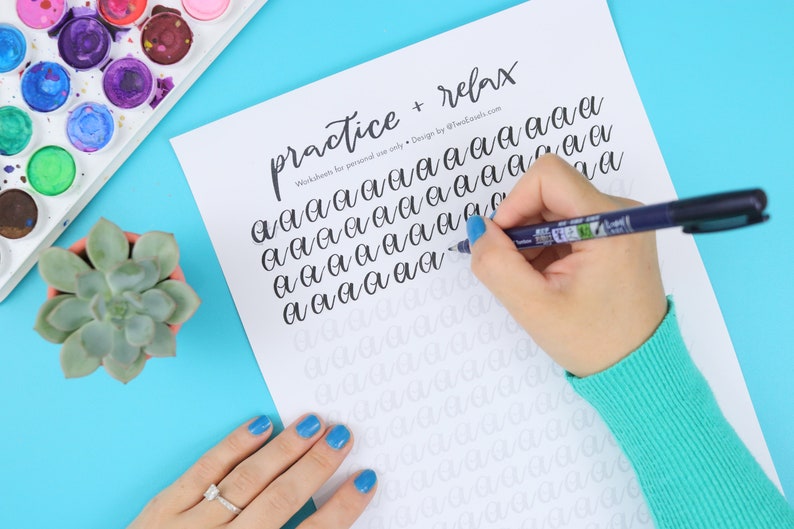 May include: A calligraphy practice sheet with the words "practice + relax" at the top. The sheet is filled with the letter "a" in various cursive styles. A person's hand is shown tracing the letter "a" with a black pen.