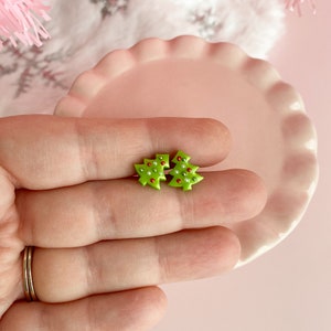 May include: A pair of green Christmas tree earrings with red and white beads.
