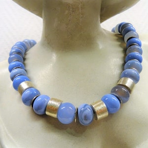May include: A light blue agate bead necklace with silver accents. The beads are round and have a smooth, polished finish.