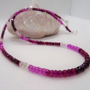 May include: A pink, purple, and white ombre gemstone necklace with faceted beads. The necklace is made of natural gemstones and is strung on a silver chain.
