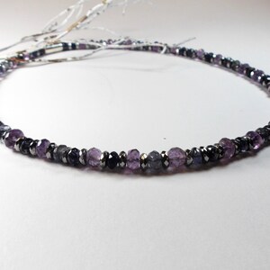May include: A silver necklace with purple and black gemstone beads.