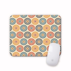 May include: A mouse mat with a repeating pattern of colourful circles with radiating lines. The circles are in shades of red, orange, yellow, blue, and green. The background is a light cream colour.