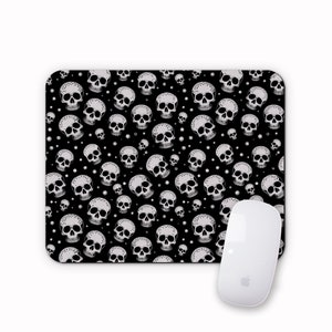 May include: Black mouse mat with a white skull pattern. The skulls are arranged in a repeating pattern on a black background.