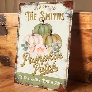 May include: A rusty metal sign with a white background and gold lettering. The sign reads "Welcome to The Smiths Pumpkin Patch Melissa, James, Rose & Josh". There are three pumpkins in the centre of the sign, one white, one green, and one brown. The pumpkins are surrounded by pink and white flowers.