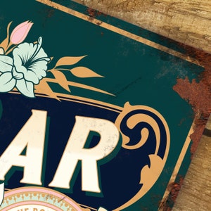 Pu&ograve; includere: Un cartello in metallo in stile vintage con sfondo verde e dettagli dorati. Il cartello presenta la parola "BAR" in lettere bianche con un motivo floreale decorativo in alto.