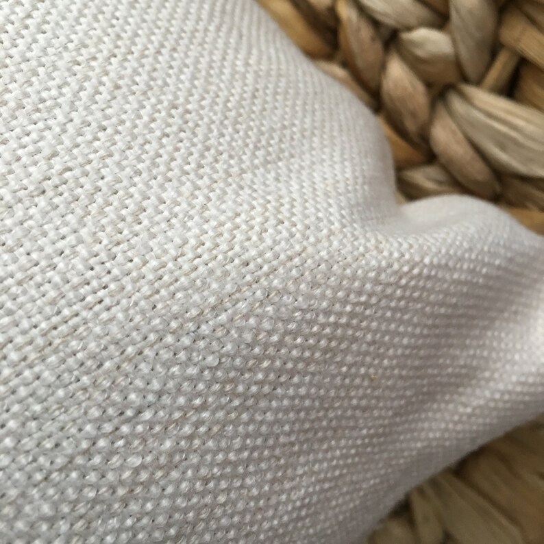 May include: Close-up of a white fabric with a woven texture. The fabric is soft and has a subtle sheen.
