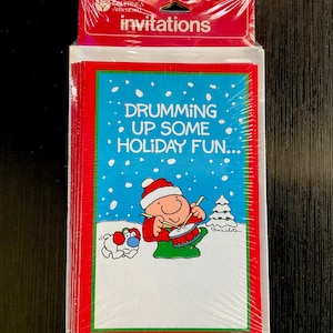 May include: Sealed package of Christmas invitations. The invitations have a red and green border with a blue background. The illustration shows a cartoon character drumming with a dog in the snow. Text reads "Drumming Up Some Holiday Fun..."
