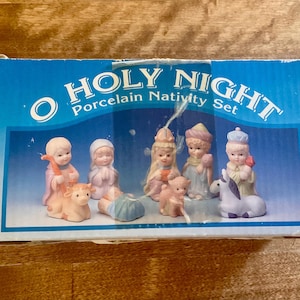 May include: A rectangular blue cardboard box labeled O HOLY NIGHT Porcelain Nativity Set. The box features a printed image of several small porcelain figurines, including human figures in robes and animals, arranged in a group.