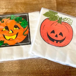 May include: Two packages of white paper napkins with orange jack-o'-lantern designs. One design has a black border, while the other is a simple pumpkin. Both have green vines and leaves. Perfect for Halloween.