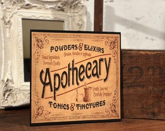 May include: A square wooden sign with a tan background and black text reading Powders & Elixirs, Apothecary, and Tonics & Tinctures. The design includes decorative corner flourishes and a small illustration of a mortar and pestle set.