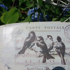 May include: An oval-shaped wooden plaque with a distressed white finish featuring a graphic of four birds perched on musical staff lines. The text reads CARTE POSTALE, Ce c&ocirc;t&eacute; est exclusivement r&eacute;serv&eacute; &agrave; l'adresse, and a circular stamp with 1909.