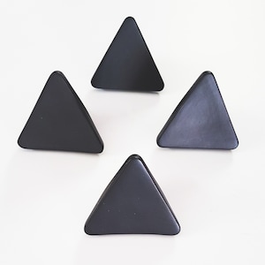 May include: Four black triangle-shaped ceramic wall hooks.