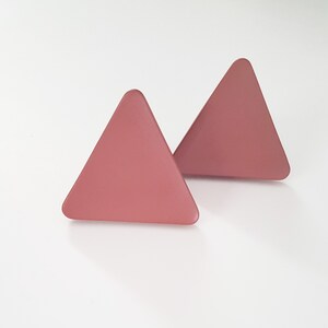May include: A pair of pink triangle shaped earrings.