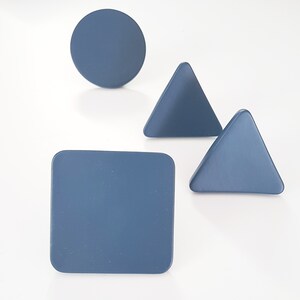 May include: Four blue geometric shapes: a circle, a square, and two triangles. The shapes are made of wood and have a matte finish.