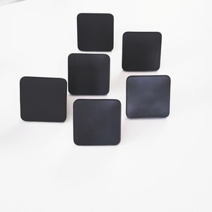 May include: Six black square-shaped coasters.