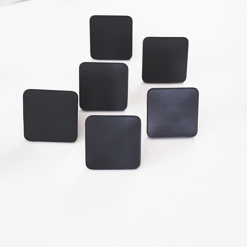May include: Six black square-shaped coasters.