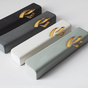 May include: Four rectangular boxes in black, gray, white, and light green with a gold design on top. The boxes are arranged in a row from left to right, with the black box at the top and the light green box at the bottom.