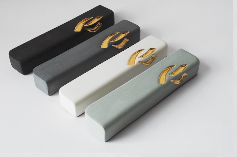May include: Four rectangular boxes in black, gray, white, and light green with a gold design on top. The boxes are arranged in a row from left to right, with the black box at the top and the light green box at the bottom.