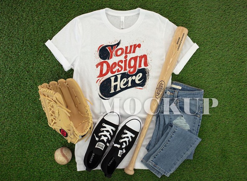 May include: A white t-shirt with the text "Your Design Here", alongside a baseball bat, jeans, a baseball glove, a baseball, and black trainers. The items are arranged on a green surface.
