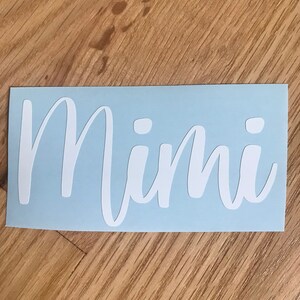 May include: A light blue vinyl sticker with the word "Mimi" written in white cursive lettering.