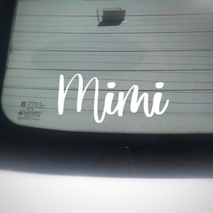 May include: White vinyl decal with the word "Mimi" written in a cursive font on a car window.