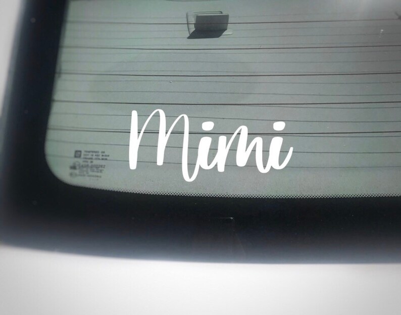 May include: White vinyl decal with the word "Mimi" written in a cursive font on a car window.