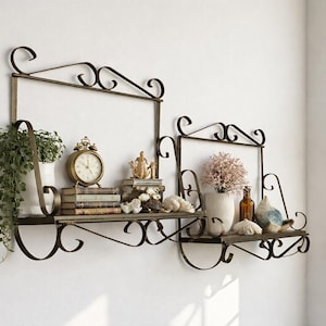 May include: Ornate, dark metal wall shelves with decorative scrollwork. The shelves hold a variety of items, including a potted plant, books, a vintage clock, vases, and decorative objects. The shelves are mounted on a white wall.