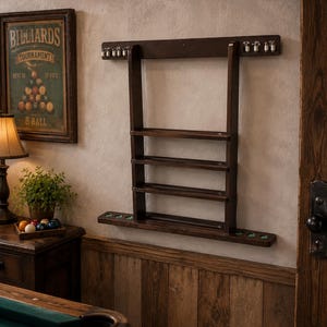May include: A dark brown wooden wall-mounted billiard cue rack featuring three horizontal shelves for storage, a top bar with small metal clips, and a bottom base with circular cutouts for cue tips, designed to hold multiple pool cues securely.