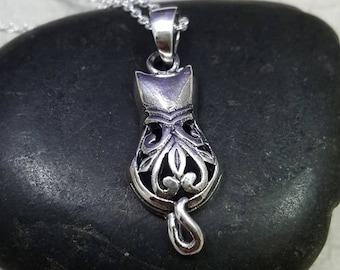 May include: A silver necklace with a detailed, filigree cat pendant. The cat is facing forward with its tail curled up behind it.