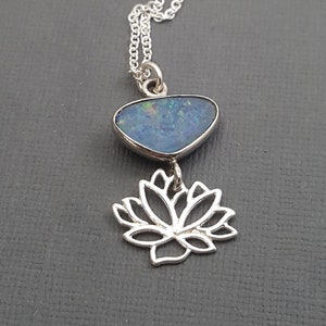 May include: A silver necklace with a blue opal pendant and a silver lotus flower charm.