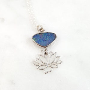 May include: A silver necklace with a blue opal pendant and a silver lotus flower charm.