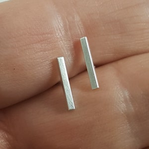 May include: A pair of silver bar stud earrings. The earrings are simple and minimalist, and they are perfect for everyday wear.