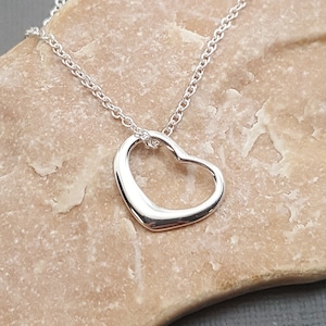 May include: A silver necklace with a delicate open heart pendant.