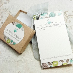 May include: A small brown box with a white circle sticker that says "The Wren and Rabbit" with a green and blue floral design. The box is sitting on a white surface next to a white card with the same floral design and the text "The Wren and Rabbit" and "www.etsy.com/shop/thewrenandrabbit".