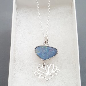 May include: A silver chain necklace with a blue opal pendant and a silver lotus flower charm.