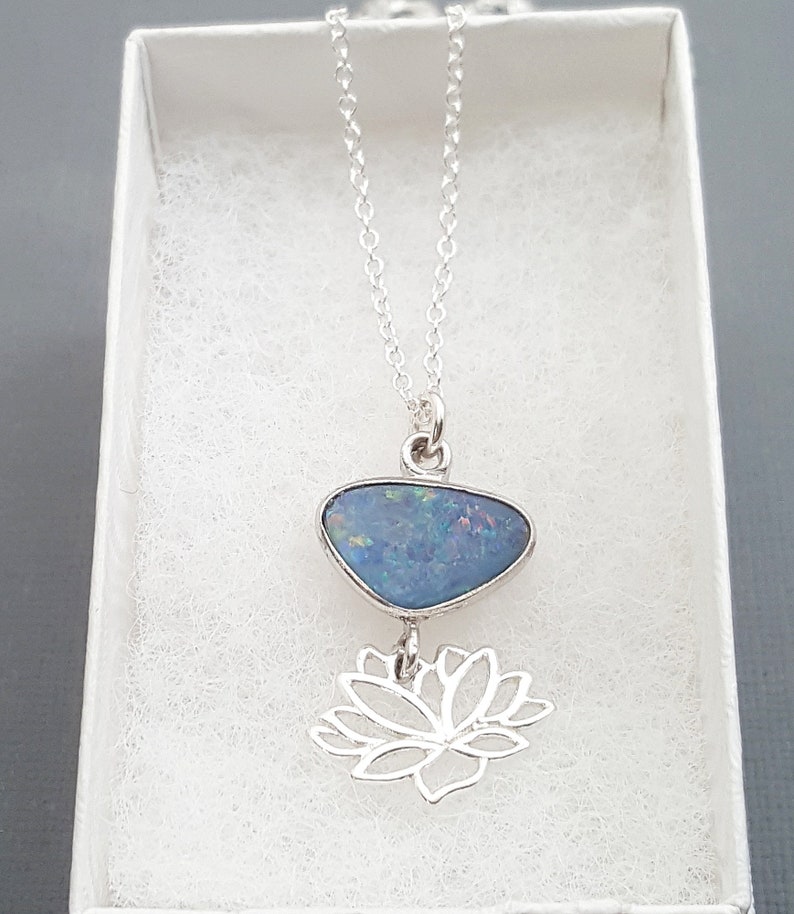 May include: A silver chain necklace with a blue opal pendant and a silver lotus flower charm.