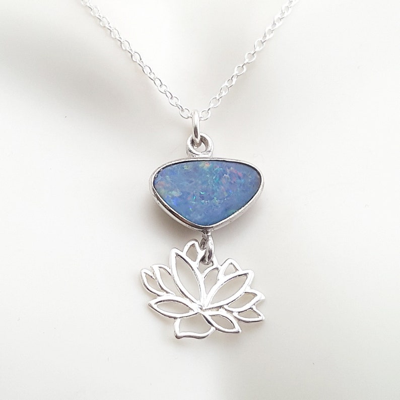 May include: A silver necklace with a blue opal pendant and a silver lotus flower charm.