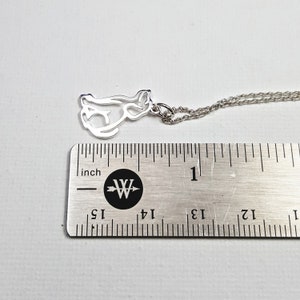 May include: Silver necklace with a cutout cat pendant. The pendant is about 1 inch long and is on a silver chain.