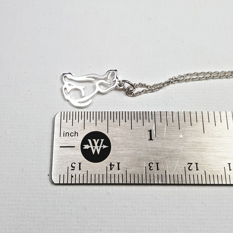 May include: Silver necklace with a cutout cat pendant. The pendant is about 1 inch long and is on a silver chain.